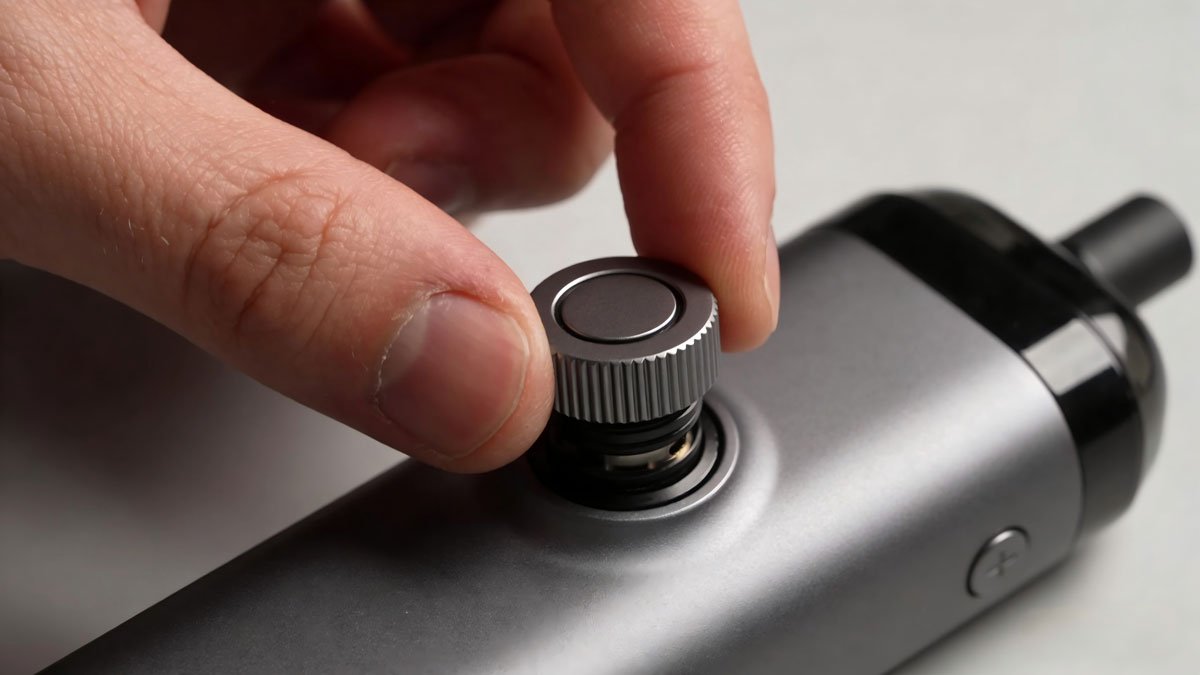 A person's hand making a fine adjustment to the airflow control on a modern pod system.