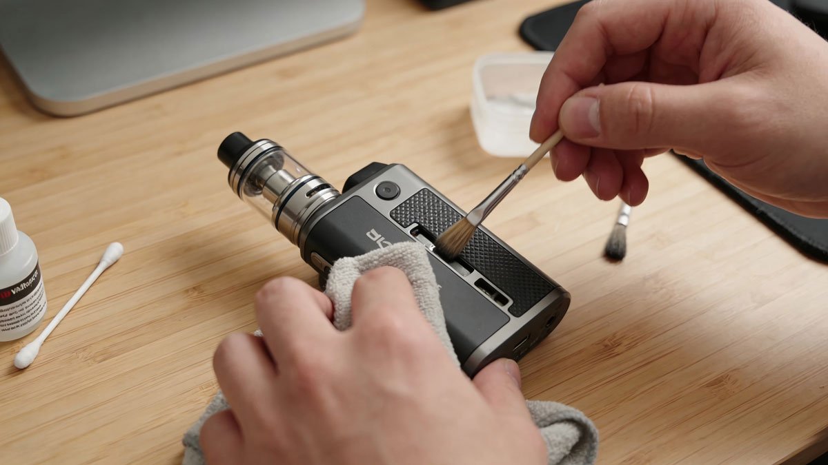 Person cleaning a vape device on a desk